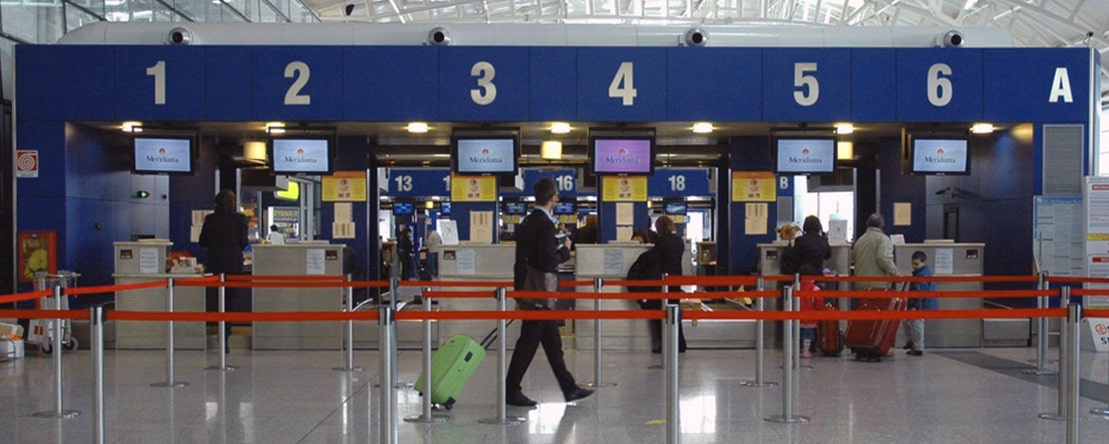 Fotografia presa all'interno dell'aeroporto di Cagliari: persone in fila al check-in