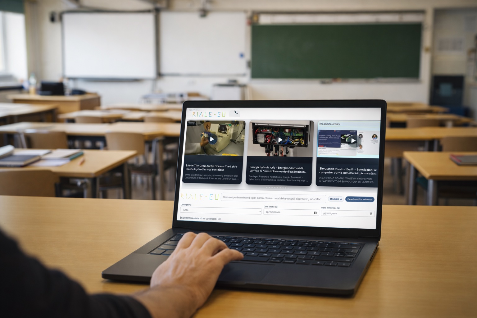 Aula scolastica con cattedra del docente su cui è poggiato un portatile e un insegnante consulta il catatlogo di RIALE-EU